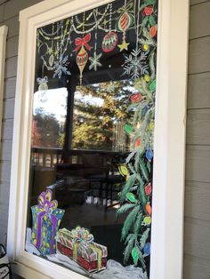 a window decorated with christmas decorations and presents in front of a tree on the outside