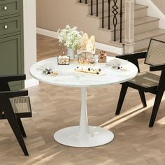 a white table with chairs around it in the middle of a room next to stairs