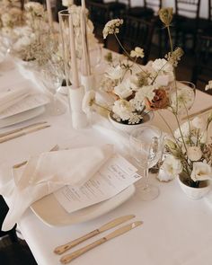 the table is set with white flowers and silverware