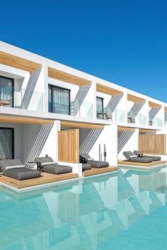 an empty swimming pool with lounge chairs next to the side of a large white building