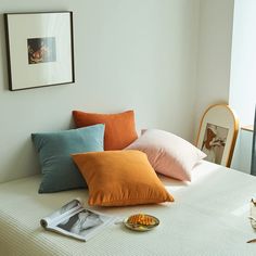 a bed with several pillows on top of it next to a framed photograph and other items