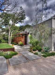 a modern house with landscaping and trees in the front yard