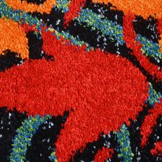 an orange, black and blue rug with red flowers