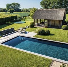 an aerial view of a pool surrounded by hedges and lawn furniture, with a thatched roof