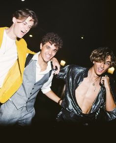 three young men standing next to each other in front of a street light at night