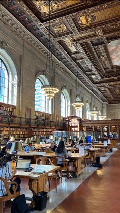 the library is full of books and people working on their laptops while sitting at tables