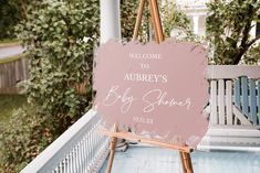 a welcome sign for a baby shower is displayed on an easel in front of a porch