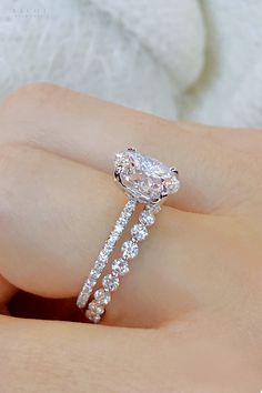 a woman's hand holding an engagement ring with a large diamond on the side