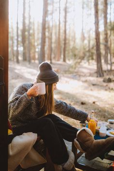 a woman sitting on top of a wooden bench in the woods