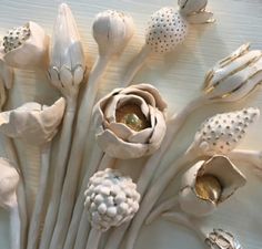 there are many white flowers that have been made out of clay and some gold in the middle