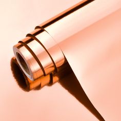 a close up view of a shiny metal object on a pink background with the light reflecting off it's surface