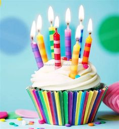 a cupcake with white frosting and lit candles on it, surrounded by confetti