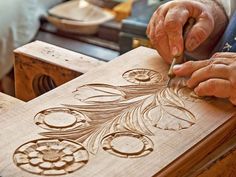 two hands are carving designs on a piece of wood