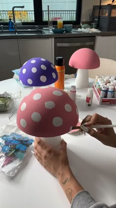 a person is cutting paper with scissors and mushroom decorations on the table in front of them