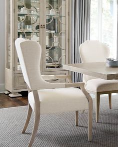 a dining room table and chairs in front of a china cabinet with glass doors on it