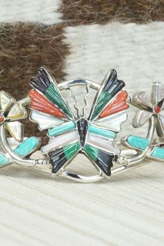 This turquoise, coral, mother of pearl, jet and sterling silver inlay butterfly bracelet was made by Zuni silversmith Tamara Pinto. The inside is stamped sterling.Size: 5 1/8" (will fit up to a 6 1/4" wrist)Gap: 1 1/8"Length: 1 1/4"Free shipping on all orders! We ship with USPS and always include tracking. All orders ship within a day of payment.Returns are accepted up to 30 days after you receive your order. Just send us a message. Our shop offers cash back or store credit. The item must be ret Multicolor Sterling Silver Bracelet With Inlay, Multicolor Inlay Sterling Silver Bracelets, Multicolor Sterling Silver Bracelets With Inlay, Southwestern Sterling Silver Inlay Bracelet Gift, Butterfly Bracelet, American Jewelry, Multi Stone, Native American Jewelry, Free Jewelry