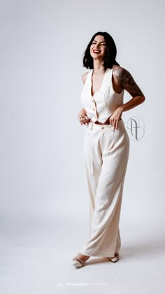 a woman in white jumpsuits posing for a photo with her hands on her hips