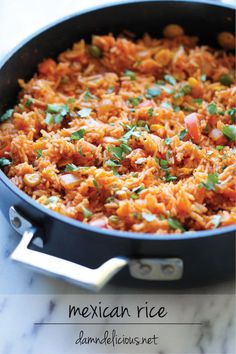 mexican rice in a skillet with cilantro and green garnishes