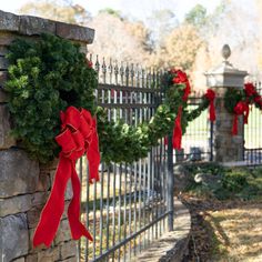 wreaths are hung on the fence with red bows