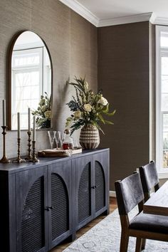 a dining room table with chairs and a vase filled with flowers