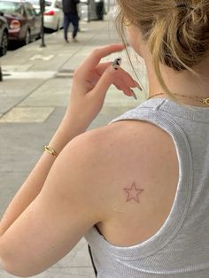 a woman with a star tattoo on her left shoulder and right arm behind her ear