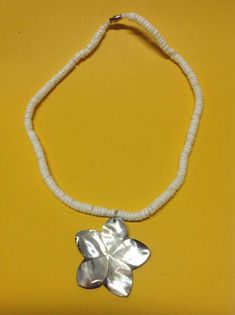 a silver flower necklace on a yellow background