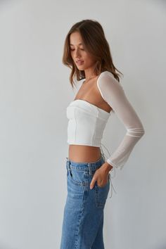 So trendy in the Rio Corset Shrug Set! This corset top is complete with a strapless fold over neckline, a lace up back with silver grommets, and a mesh long sleeve shrug. Available in black and white. Pair with your favorite jeans to complete the look! Details Top self: 95% Nylon, 5% Spandex Top lining 92% Polyester, 8% Spandex Shrug self: 90%, Nylon, 10% Spandex Shrug lining: 92% Polyester, 8% Spandex Item sold as set Silicon grips Boning Material has some stretch Machine wash cold / Tumble dry Chic White Top With Corset Back, White Boned Bodice Top For Evening, White Stretch Top With Boned Bodice, White Stretch Tops With Boned Bodice, Spring Long Sleeve Fitted Corset, Spring Stretch Crop Top With Corset Back, Summer Long Sleeve Corset, White Long Sleeve Corset For Spring, Spring Tops With Stretch Boned Bodice