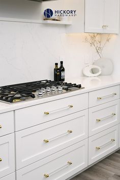 a kitchen with white cabinets and gold knobs on the stove top is pictured in this image