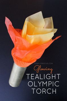 an orange and yellow flower made out of tissue paper on top of a black surface