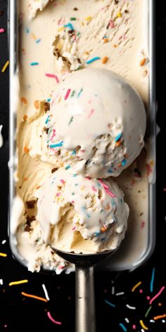 two scoops of ice cream with sprinkles in a metal container on a black surface