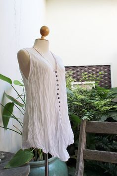 "This lovely sleeveless top made of 100% Thai dyed soft and light cotton with coconut buttons at front and colorful hand-thread embroidery along the neckline. The A Shape provide you more comfort and style.      This piece is very comfortable to wear and easy to care for, if you like - no need to iron. Just twist to make crinkle and keep it in your closet.  Fits great for S-L A-Line shape Uneven hemline/ could be tied at front  Opened coconut buttons The actual color of this item is a bit richer Cotton Button Tank Top For Beach, V-neck Buttoned Tank Top For The Beach, V-neck Tank Top With Buttons For Beach, V-neck Buttoned Tank Top For Beach, Beach Tank Top With Buttons, Bohemian Linen Sleeveless Tank Top, Bohemian Sleeveless Linen Tank Top, Cotton V-neck Tank Top With Buttons, V-neck Cotton Tank Top With Buttons