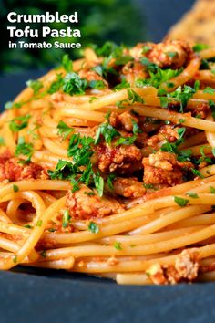 a close up of a plate of food with pasta and meat on it, text reads crumbled tofu pasta in tomato sauce