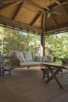 a covered porch with chairs, table and couches