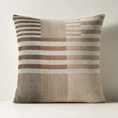 a brown and white striped pillow sitting on top of a wooden table next to a wall