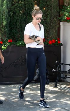 a woman in black leggings and white shirt walking with a small cat on her shoulder