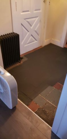 a white radiator sitting on top of a wooden floor next to a door