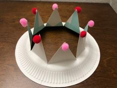 a paper plate that has some kind of crown on top of it with pom - poms