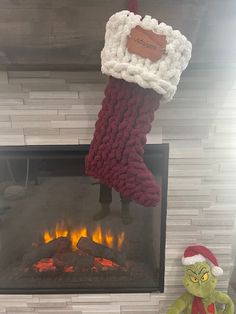 a christmas stocking hanging over a fire place with a grin face stuffed animal next to it