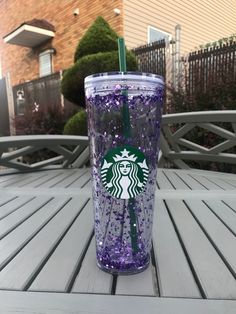 a purple starbucks cup sitting on top of a wooden table