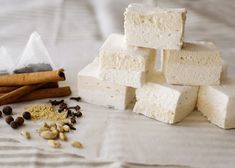 three pieces of white marshmallow sitting on top of a bed next to cinnamon sticks and spices