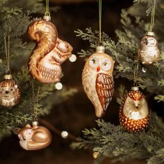 an assortment of ornaments hanging from a christmas tree in the shape of owls and squirrels