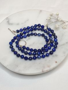 "Details: ☆ Gemstone- High quality Natural Lapis Lazuli, faceted round shape, 5mm  ☆ Closure- 925 Sterling silver, 12mm, a toggle clasp, twisted round ☆ Bead tip- 925 Sterling silver, 3mm ☆ Bead cap- 925 Sterling silver, 3mm, flower shape  The necklace length is 18.25\". It looks beautiful alone or layered with other necklaces.  It is a perfect gift for someone special or yourself.    All my jewelries are made with lots of love and care. Lapis Lazuli: Lapis Lazuli has many healing properties. This pretty indigo and gold gemstone is known for cleansing the throat and third eye Chakras and can be used to ward off physical attacks. As a stone geared towards wisdom and communication, Lapis Lazuli can also help connect you to clarity, integrity, and intuition." Beaded Necklace With Sterling Silver Clasp As Gift, Sapphire Necklaces With Gemstone Beads, Sapphire Gemstone Beads Round Necklace, Sapphire Faceted Beaded Necklace For Gift, Faceted Sapphire Beaded Necklace Gift, Sapphire Rondelle Necklace For Gift, Sapphire Rondelle Necklace As A Gift, Sapphire Necklaces With Round Gemstone Beads, Sapphire Gemstone Beads Necklace