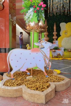 a statue of a cow is in the middle of a display with flowers and other decorations