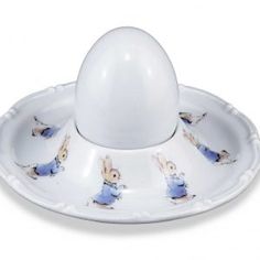 an egg sitting on top of a white plate with rabbits painted on the side and under it