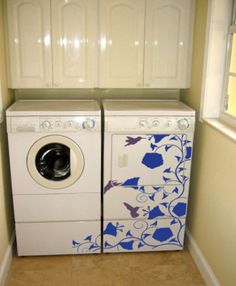 a washer and dryer in a small room with white cabinets on the wall