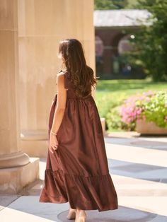 a woman in a brown dress is walking down the sidewalk