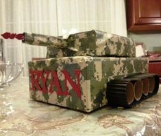 a tank made out of cardboard sitting on top of a table next to wine glasses