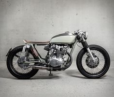 a white and black motorcycle parked in front of a cement wall with no one around it