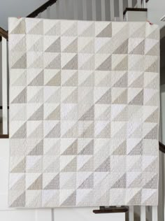 a white quilt hanging on the side of a stair case