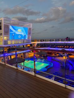 the deck of a cruise ship at night with blue lights on it and people walking around